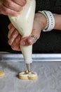 WomanÃ¢â¬â¢s hands piping vanilla frosting onto a heart shaped sugar cookie